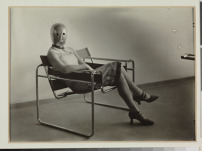 Lis Beyer or Ise Gropius sitting on the B3 club chair by Marcel Breuer and wearing a mask by Oskar Schlemmer and dress fabric by Lis Beyer, c. 1927.  