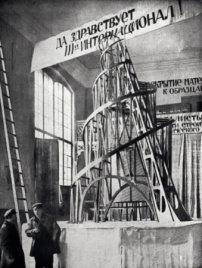 Tatlin mit Assistent vor dem Modell des Denkmals der III. Internationale, Petrograd 1920 	 