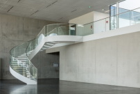 Auch im Foyer mit Wendeltreppe dominiert die Ästhetik reinen Betons. 