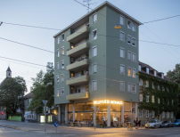 In dem fünfgeschossigen Münchner Wohnhaus gibt es eine Jugendhilfe für Geflüchtete und ein Infocafé mit Beratungsangeboten.  