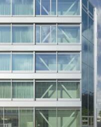 Sichtbare Konstruktionselemente und Pfosten-Riegel-Fassade mit horizontal gliedernden Aluminiumpaneelen und Glas als äußere Gestaltungsmerkmale 