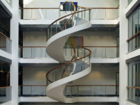 Gewendelte Faltwerktreppe mit gebogenem Glasgelnder im Foyer der KfW in Frankfurt. Bild: MetallArt Treppen