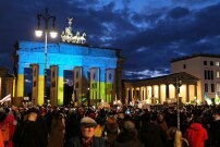 Kundgebung auf dem Pariser Platz in Berlin gegen den Einmarsch Russlands in die Ukraine vor dem mit der ukrainischen Flagge beleuchteten Brandenburger Tor.